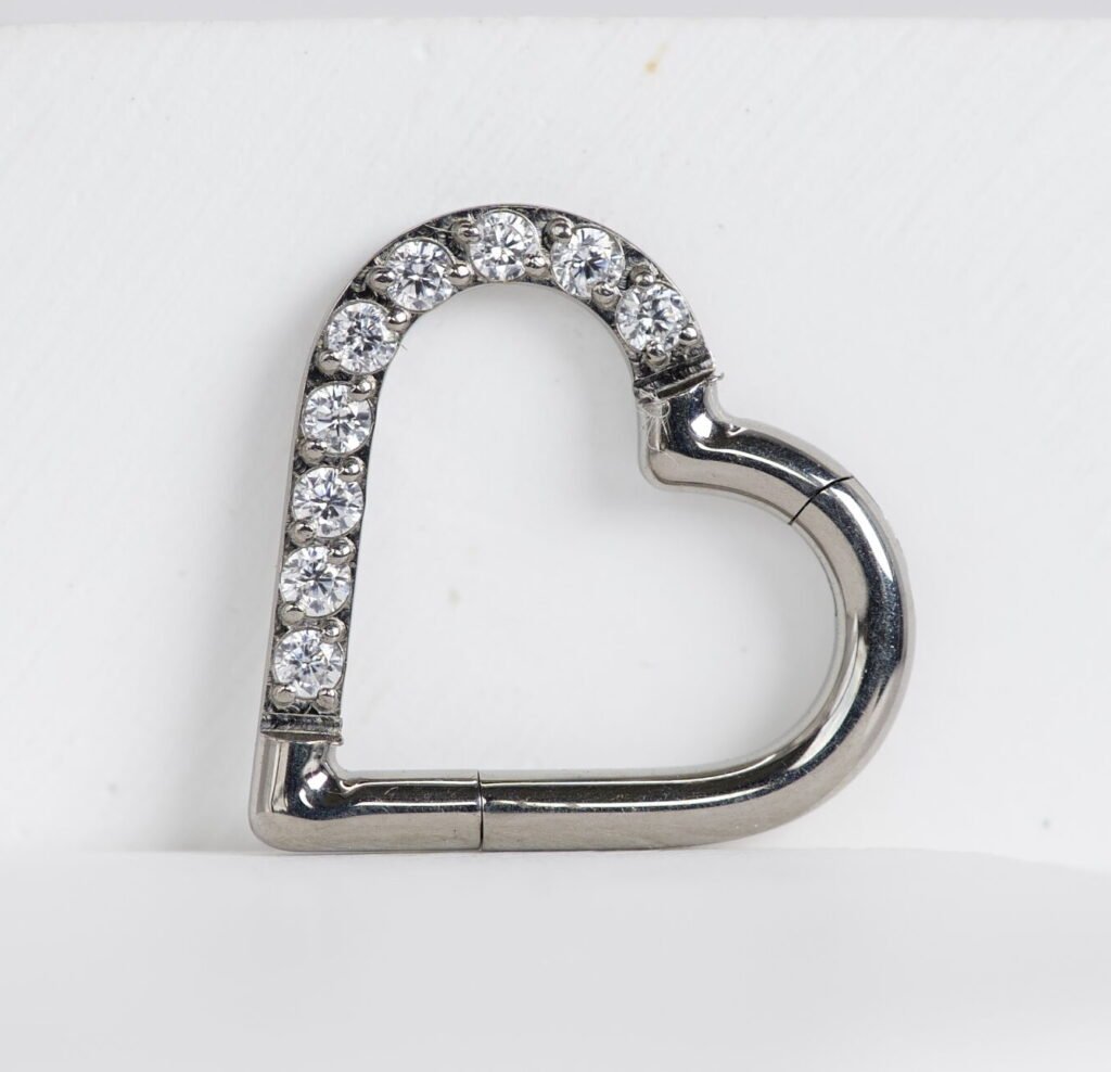 Cliker de titanio con diseño de corazón y zirconias en un costado derecho o izquierdo