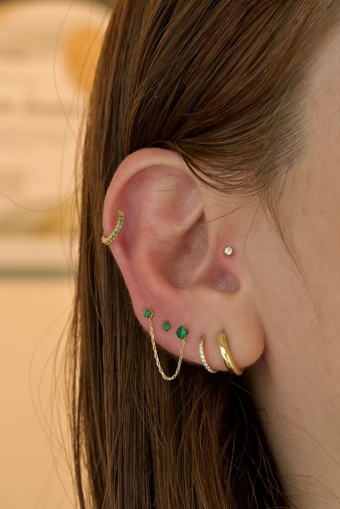 Oreja humana modelando varios piercings a la vez