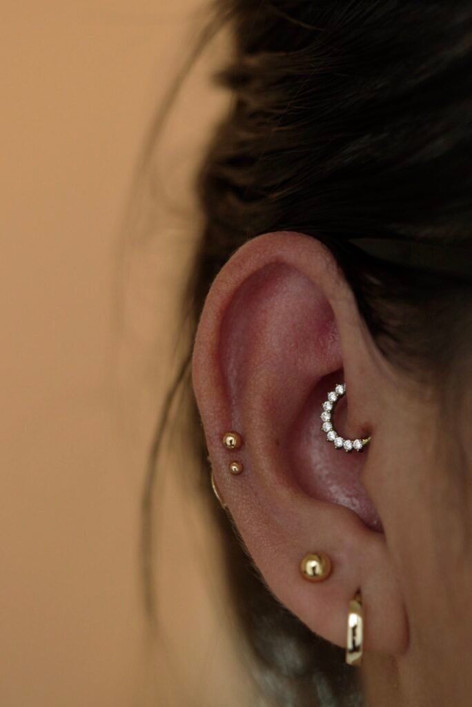 Oreja humana modelando varios piercings a la vez, uno es daith