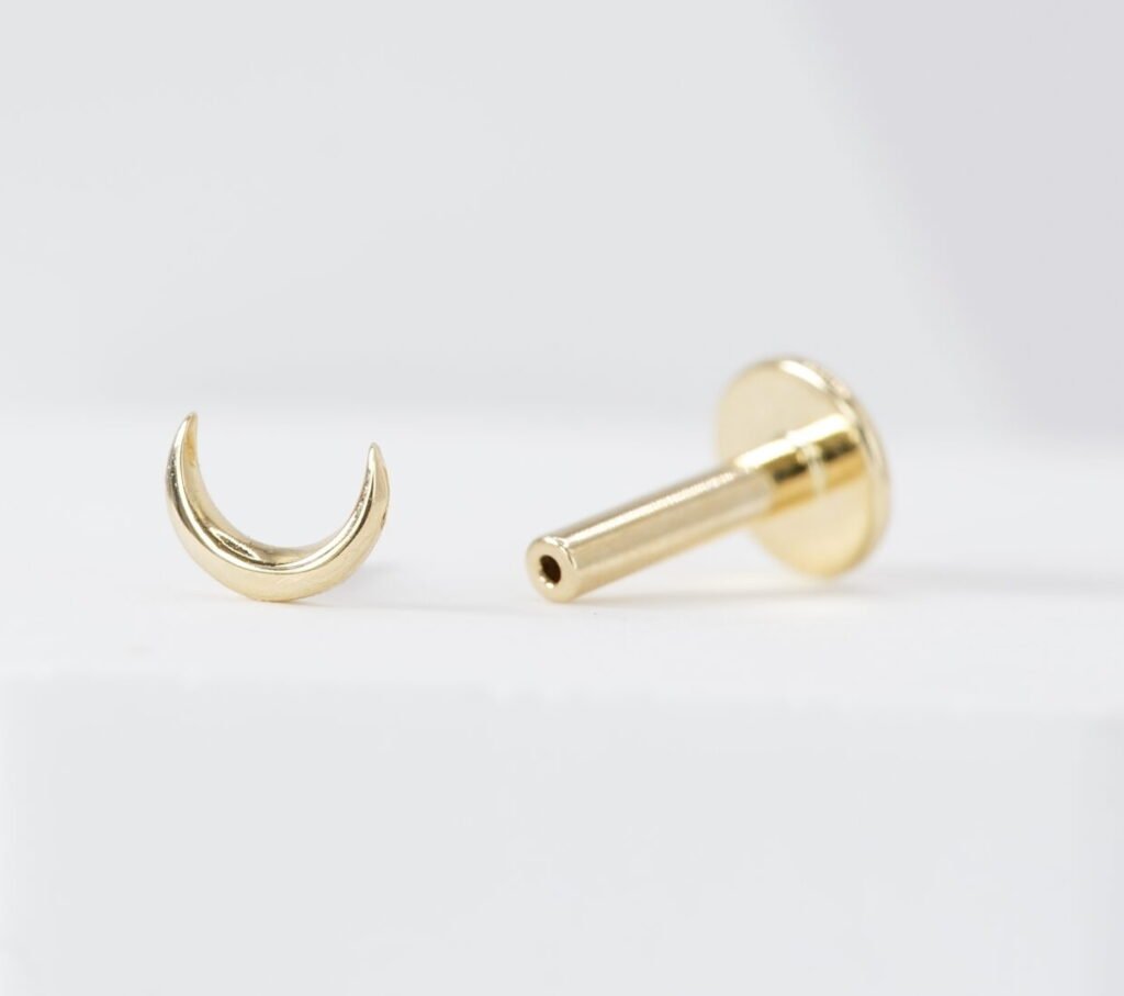 Joya de luna en oro sólido de 14K, disponible como top individual o en conjunto con labret. Un diseño delicado y elegante para complementar tu piercing.